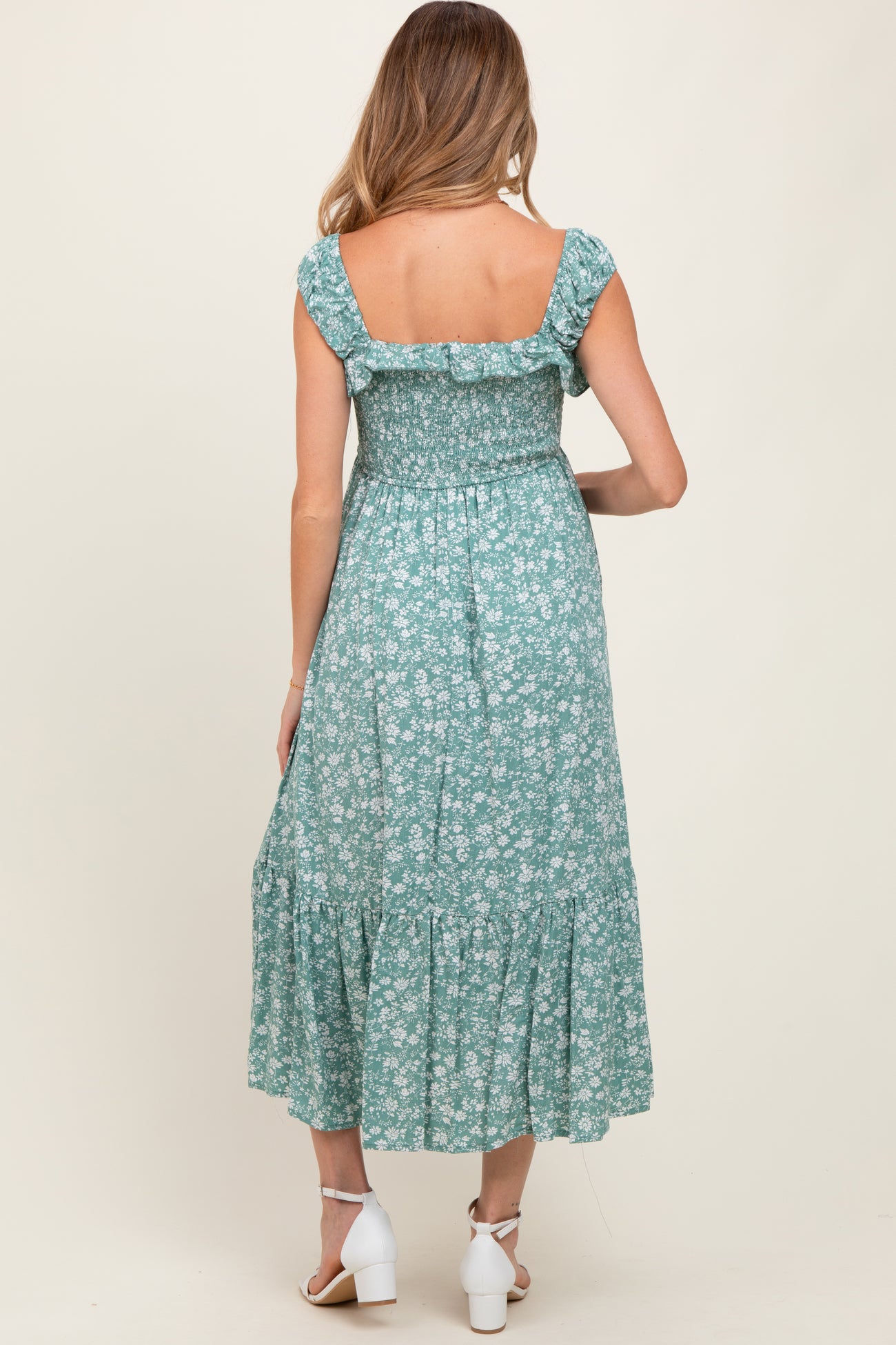 woman wearing a green floral maternity maxi dress with a smocked bodice and tiered hem, showing the back view