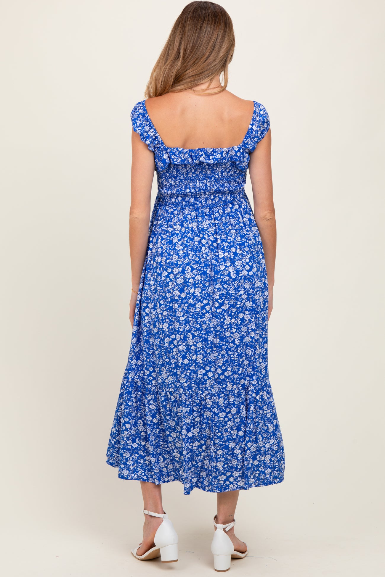 woman wearing a blue floral maternity dress with short sleeves and a tiered skirt, showing her back