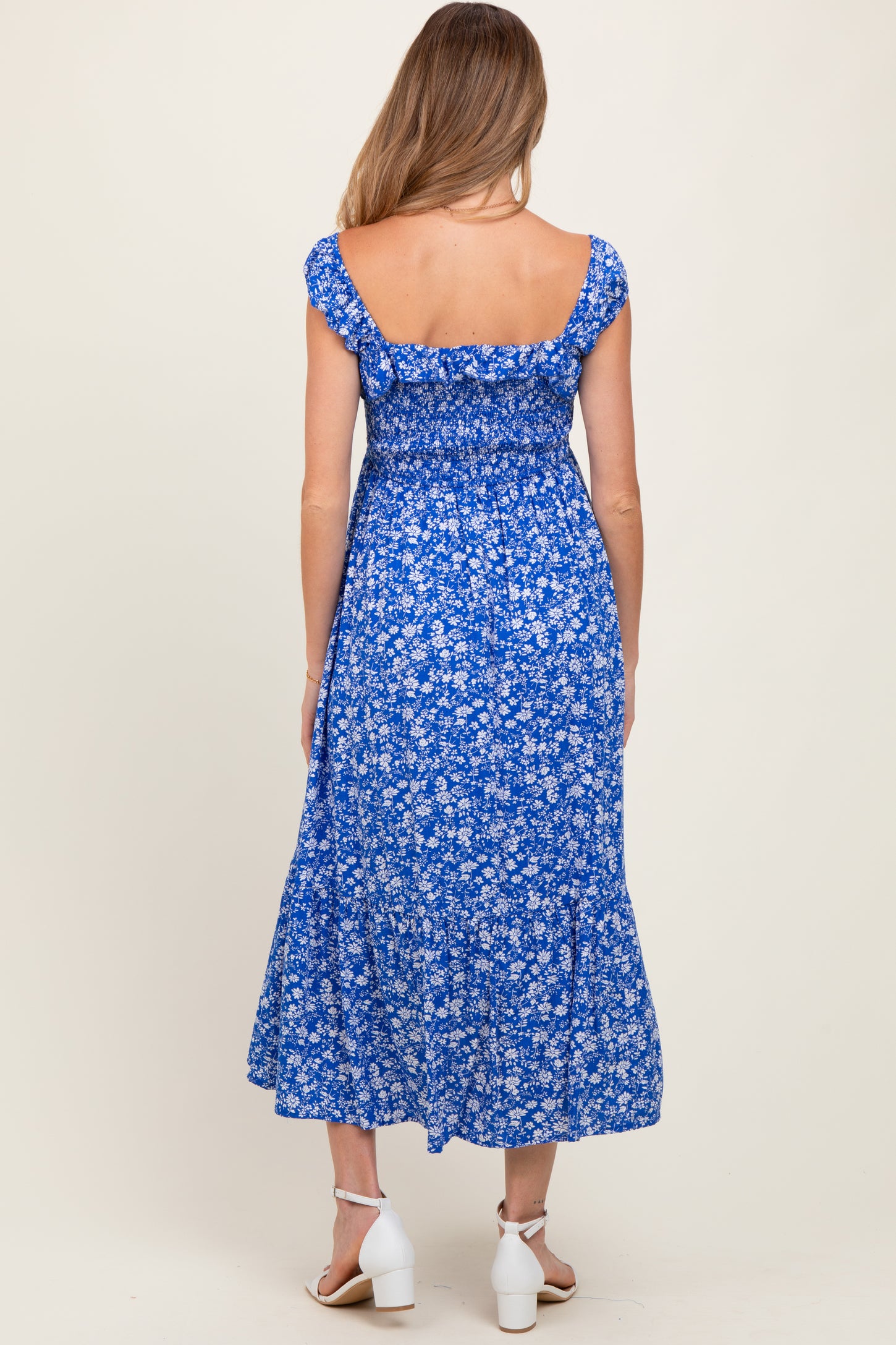 woman wearing a blue floral maternity dress with short sleeves and a tiered skirt, showing her back