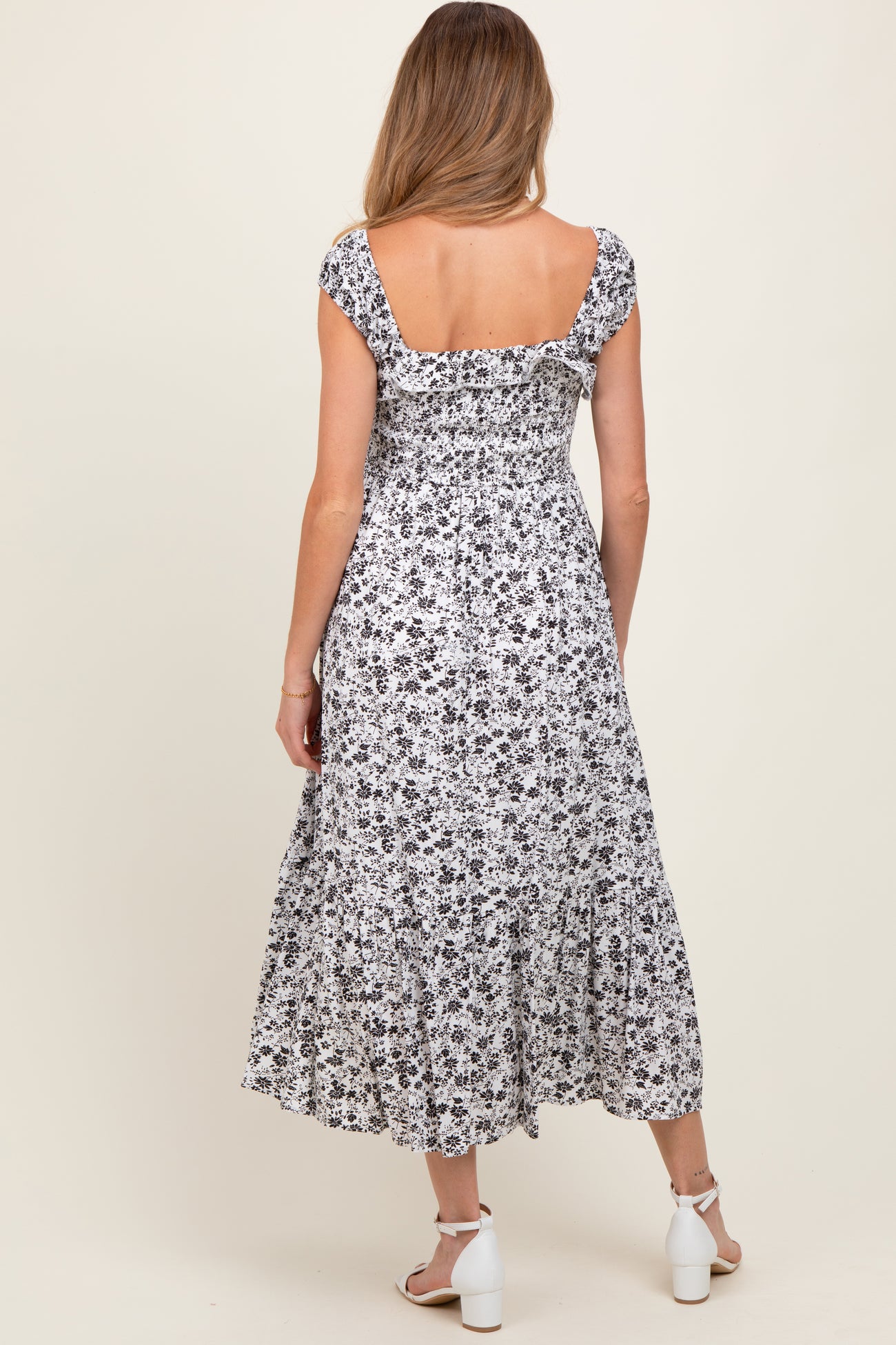 woman wearing a black and white floral maternity dress with a fitted bodice and ruffled hem