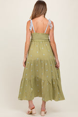 woman wearing a green floral maternity maxi dress with blue tie straps and smocked bodice