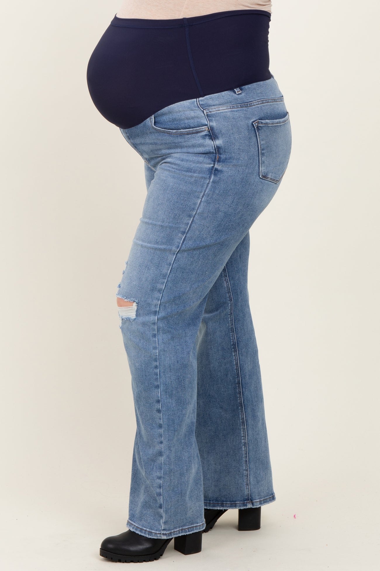 maternity plus size light wash flare jeans with distressed details and a supportive over-the-bump waistband, showing a baby bump
