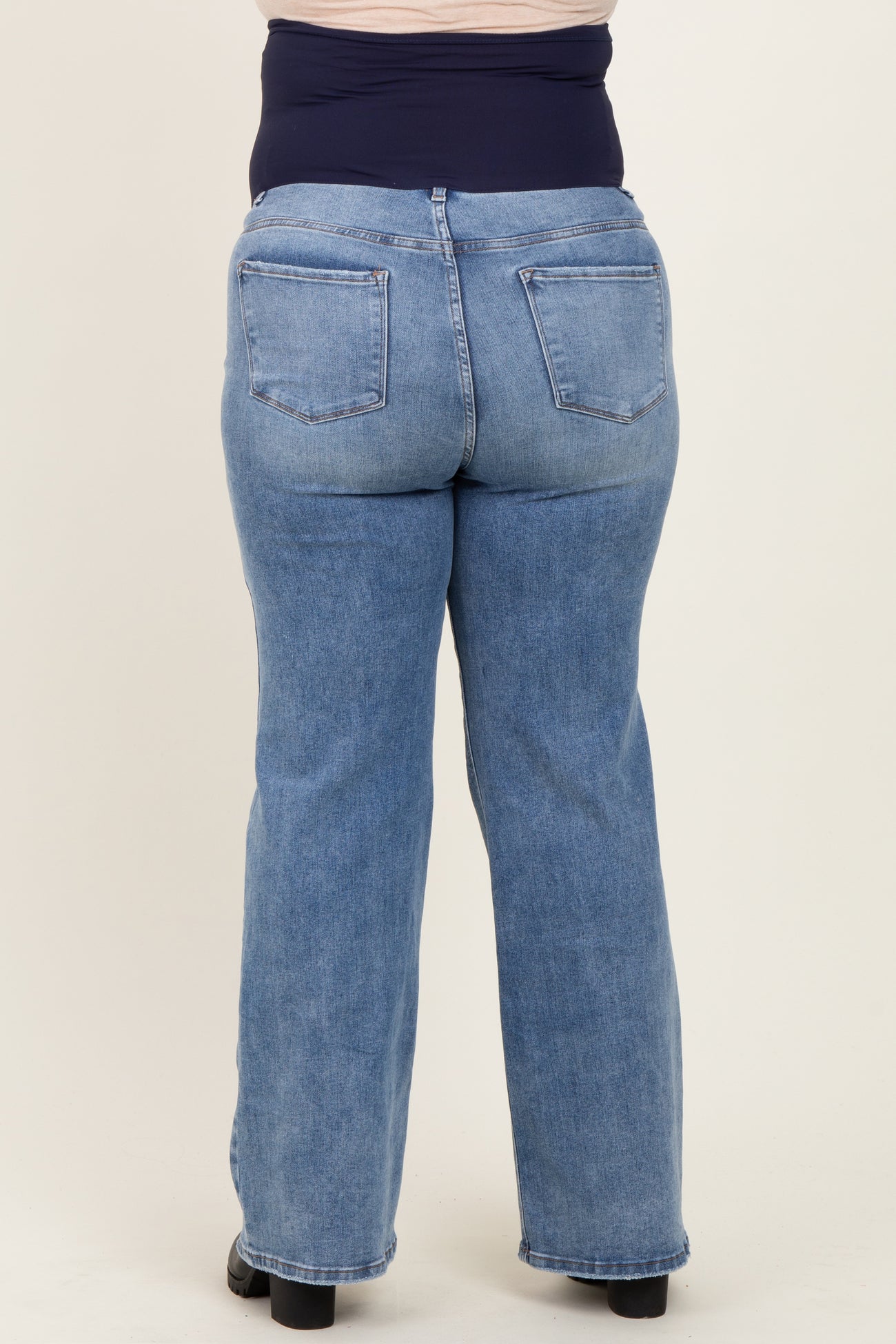 woman wearing a blue denim maternity plus jeans with a supportive waist panel, viewed from the back