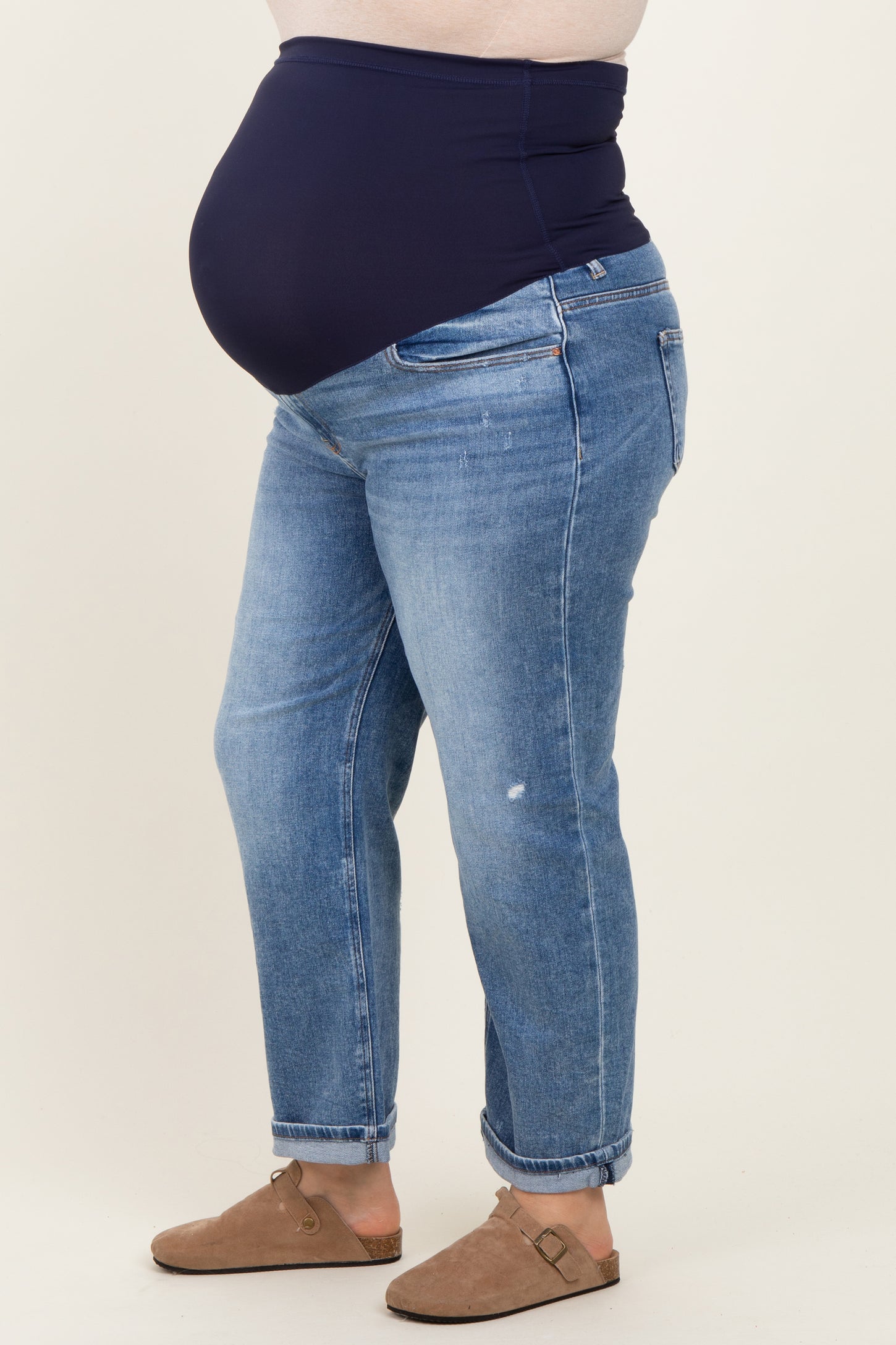 woman wearing a navy blue maternity belly band with distressed blue maternity jeans and a visible baby bump