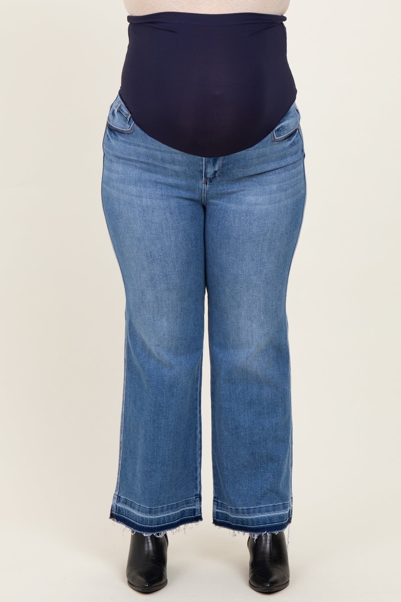 plus size woman wearing dark blue maternity jeans with a high waistband and a flared leg style