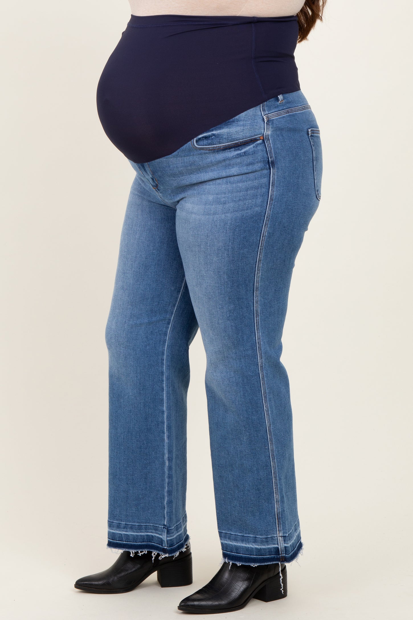 woman wearing blue maternity plus straight-leg jeans with a black belly panel, showcasing a visible baby bump