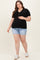 woman wearing a black ribbed maternity top with buttons and light blue denim shorts, holding her baby bump