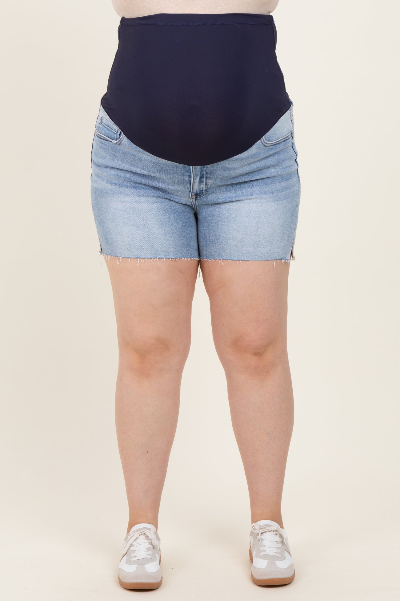 woman wearing dark blue maternity plus denim shorts with a high waistband and frayed hem