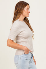 woman wearing a light beige short sleeve ribbed top with a straight hem and side pockets, styled with blue jeans