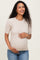 woman wearing a beige short sleeve maternity top and holding her baby bump