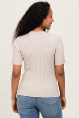 woman wearing a beige ribbed short sleeve maternity top, showing the back view