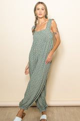 woman wearing a green floral print jumpsuit with ruffled straps and loose fit