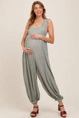 woman wearing a green floral patterned maternity jumpsuit and holding her baby bump