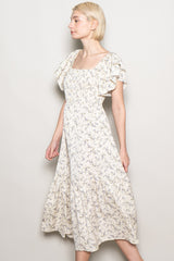 woman wearing a cream floral midi dress with flutter sleeves and a tiered hem