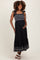 woman wearing a black maternity maxi dress with embroidered hem and smocked bodice, cradling her baby bump