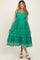 woman wearing a green sleeveless maternity dress with embroidered details and a tiered hem, showing her baby bump
