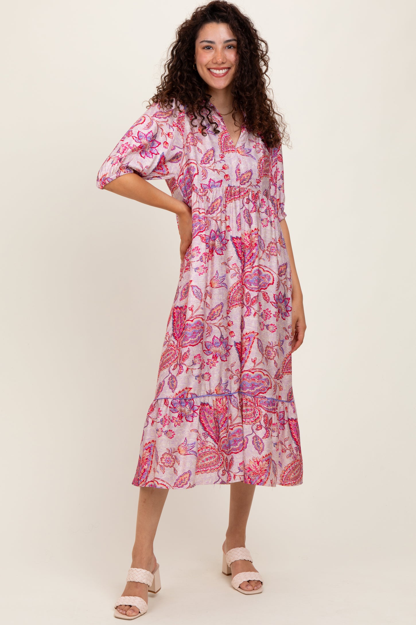 woman wearing a pink floral midi dress with short sleeves and a tiered skirt