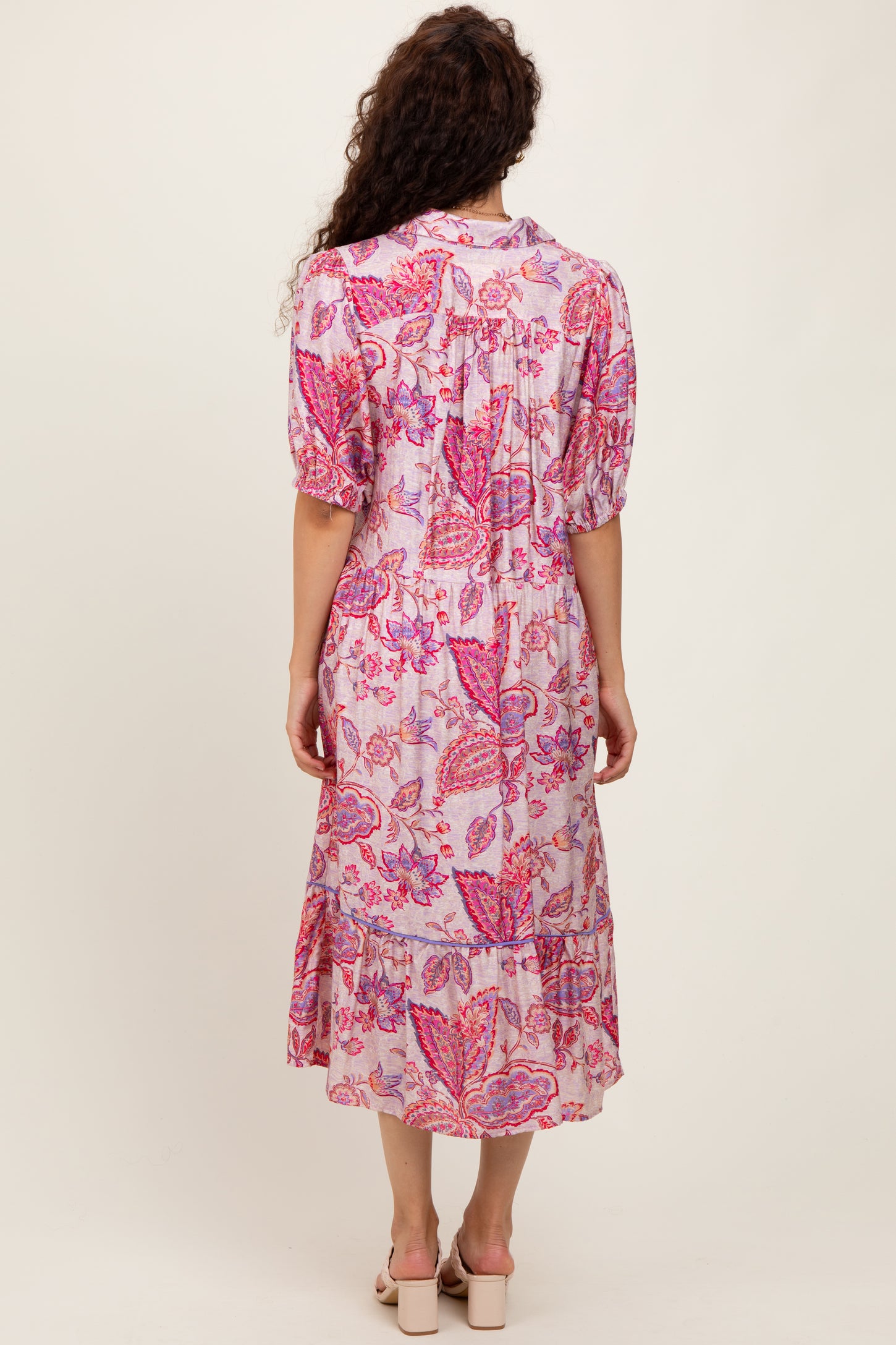 woman wearing a pink floral midi dress with puffed sleeves and a tiered skirt, viewed from the back
