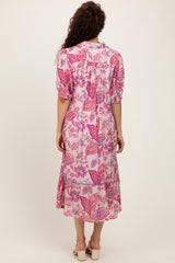 woman wearing a pink floral midi dress with puffed sleeves and a tiered skirt, viewed from the back