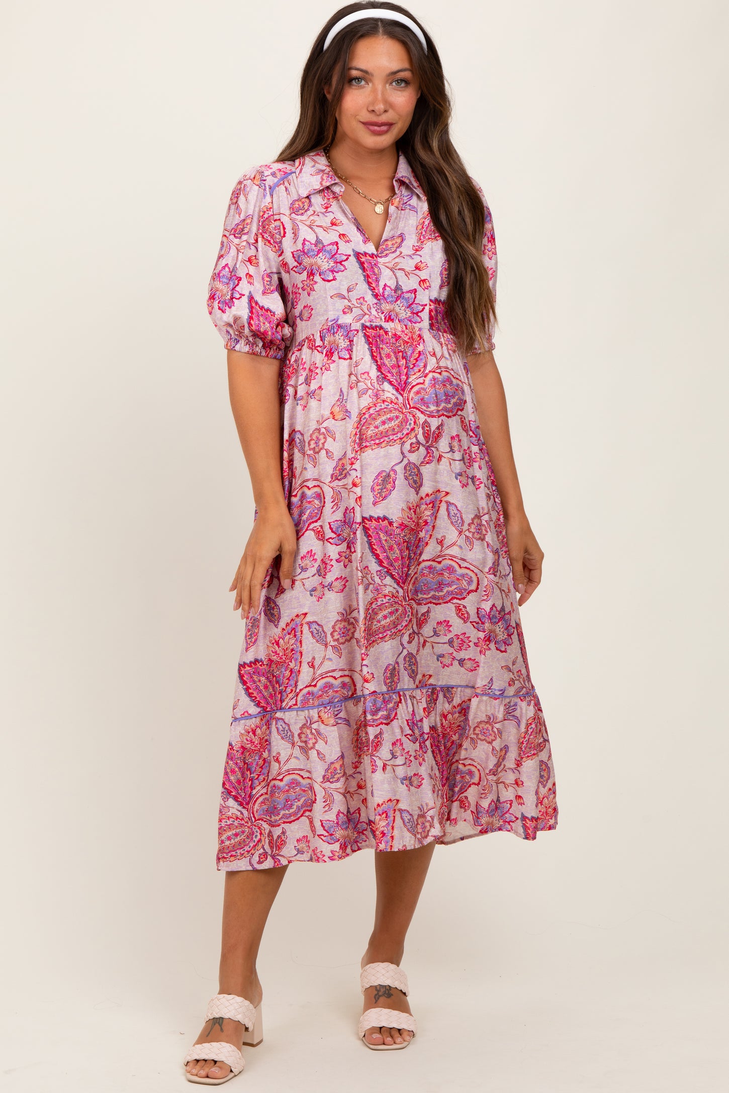 woman wearing a pink floral maternity dress with puff sleeves and a tiered skirt, showing her baby bump