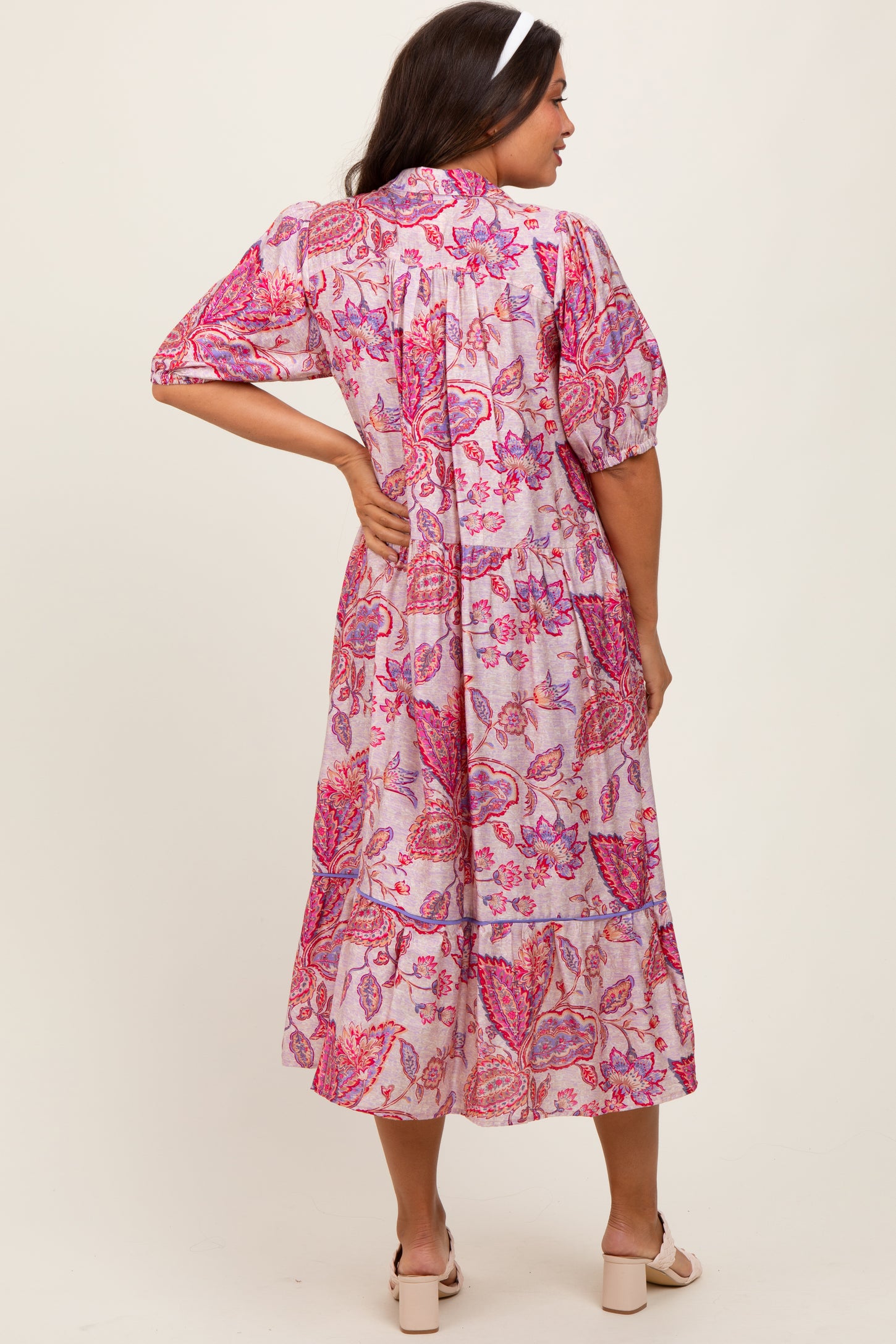 woman wearing a pink floral maternity dress with puff sleeves and a tiered skirt from the back