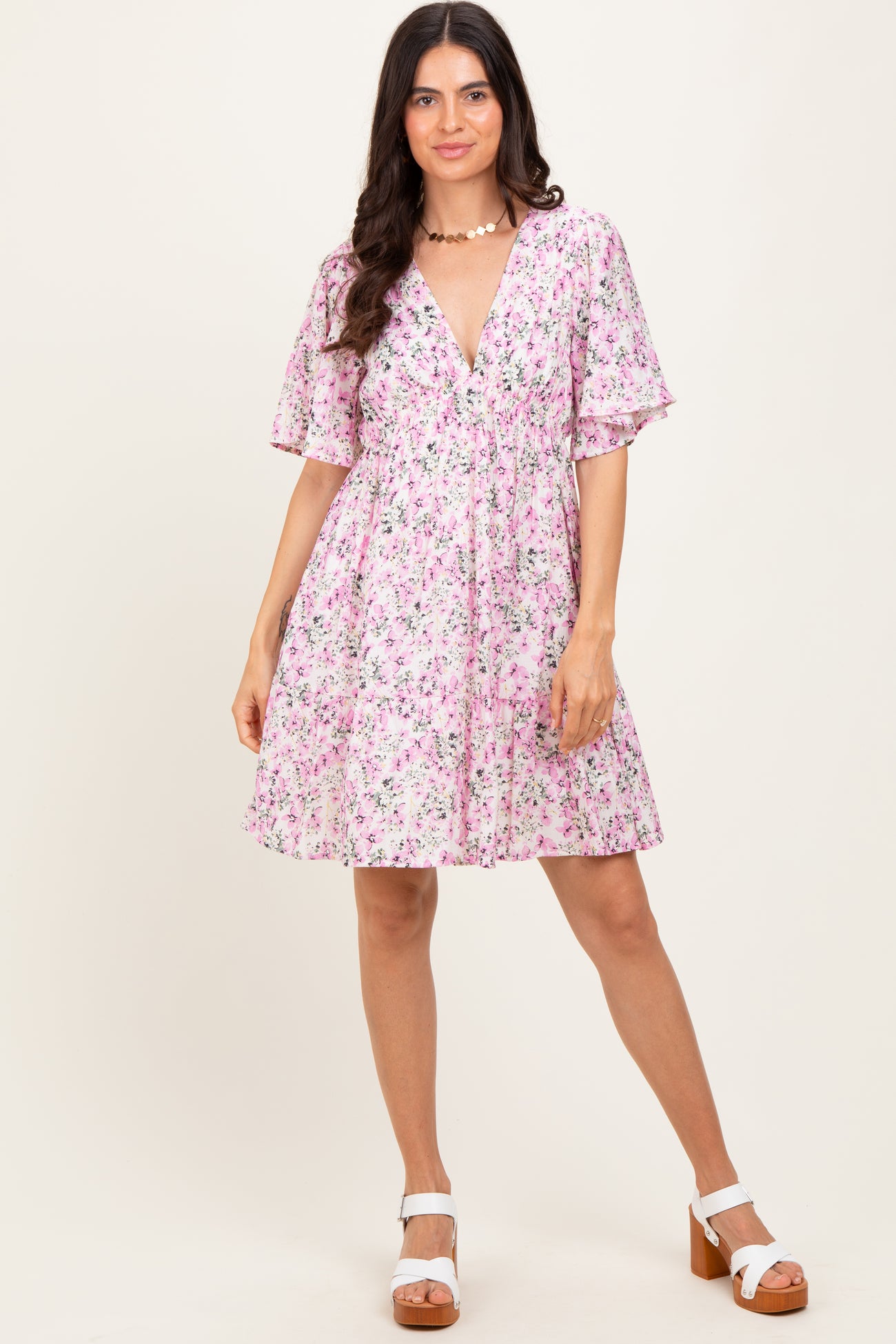 woman wearing a pink floral short sleeve dress with a v-neckline and a flared skirt