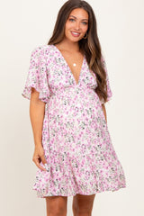 woman wearing a pink floral maternity dress with short flutter sleeves and a deep v-neckline, showing her baby bump
