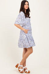 woman wearing a light blue floral short dress with pockets and flutter sleeves, paired with white platform sandals
