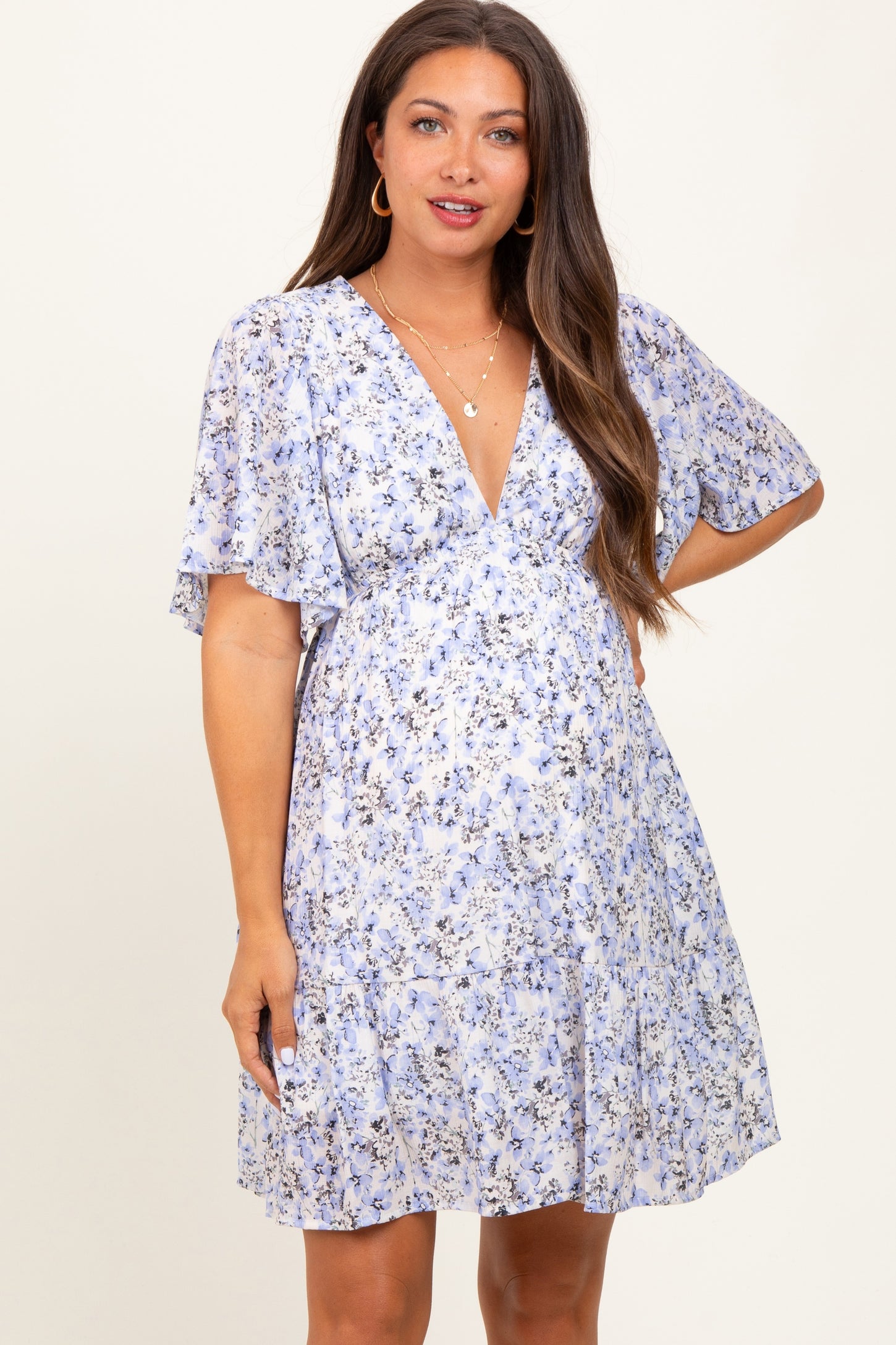 woman wearing a light blue floral maternity dress with short sleeves and a baby bump visible