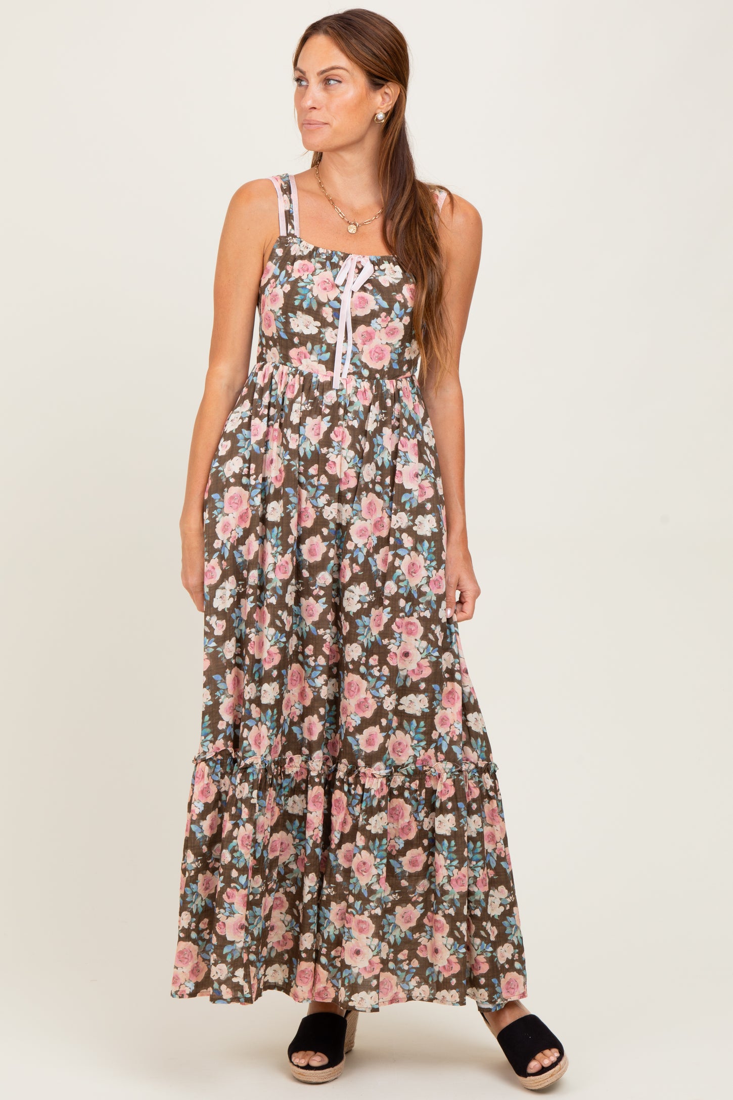 woman wearing a brown floral maxi dress with spaghetti straps and a tiered skirt