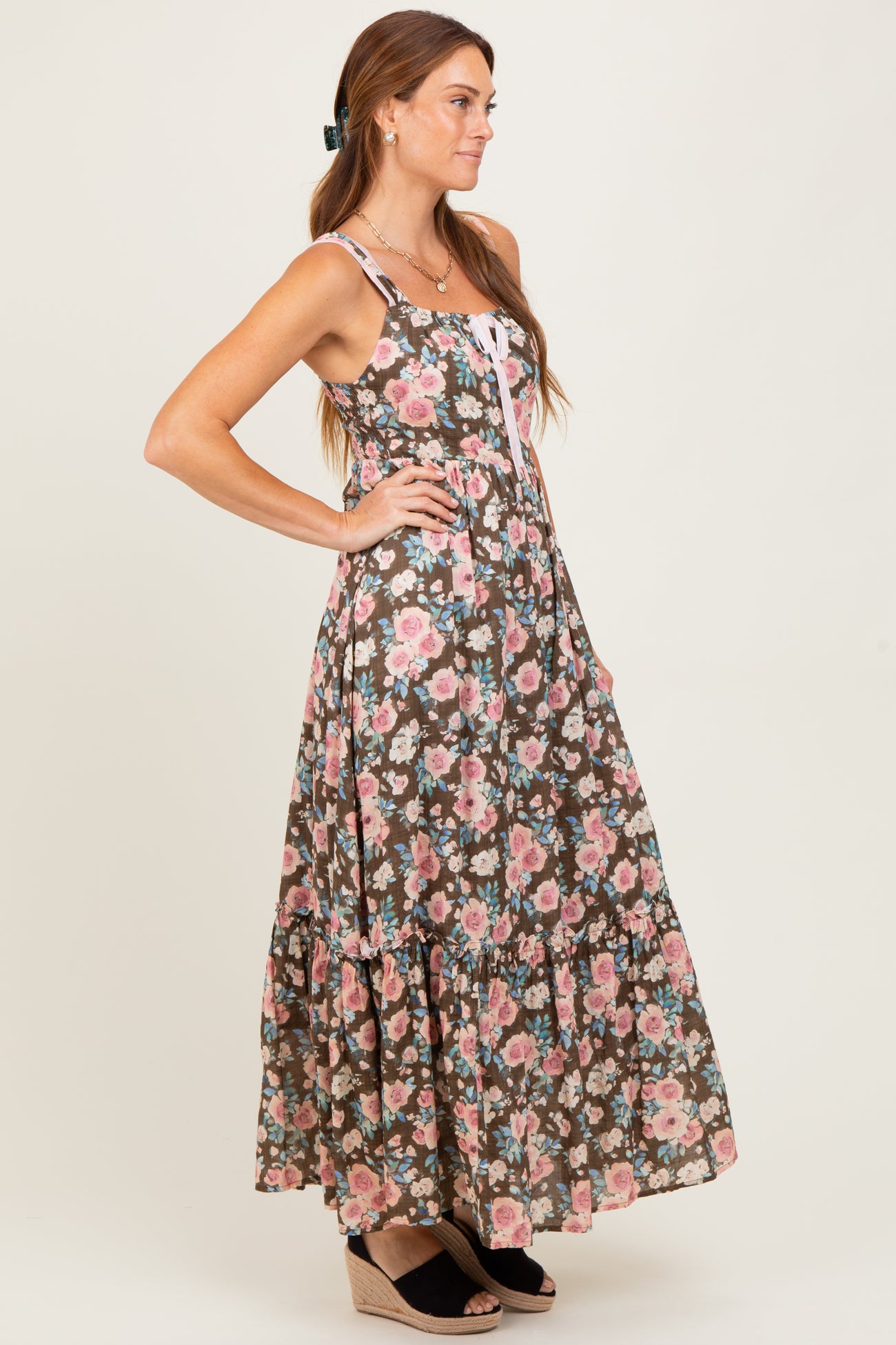 woman wearing a brown floral maxi dress with adjustable straps and a tiered skirt