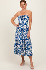 woman wearing a strapless blue and white zebra print maxi dress with a cinched waist and tiered skirt