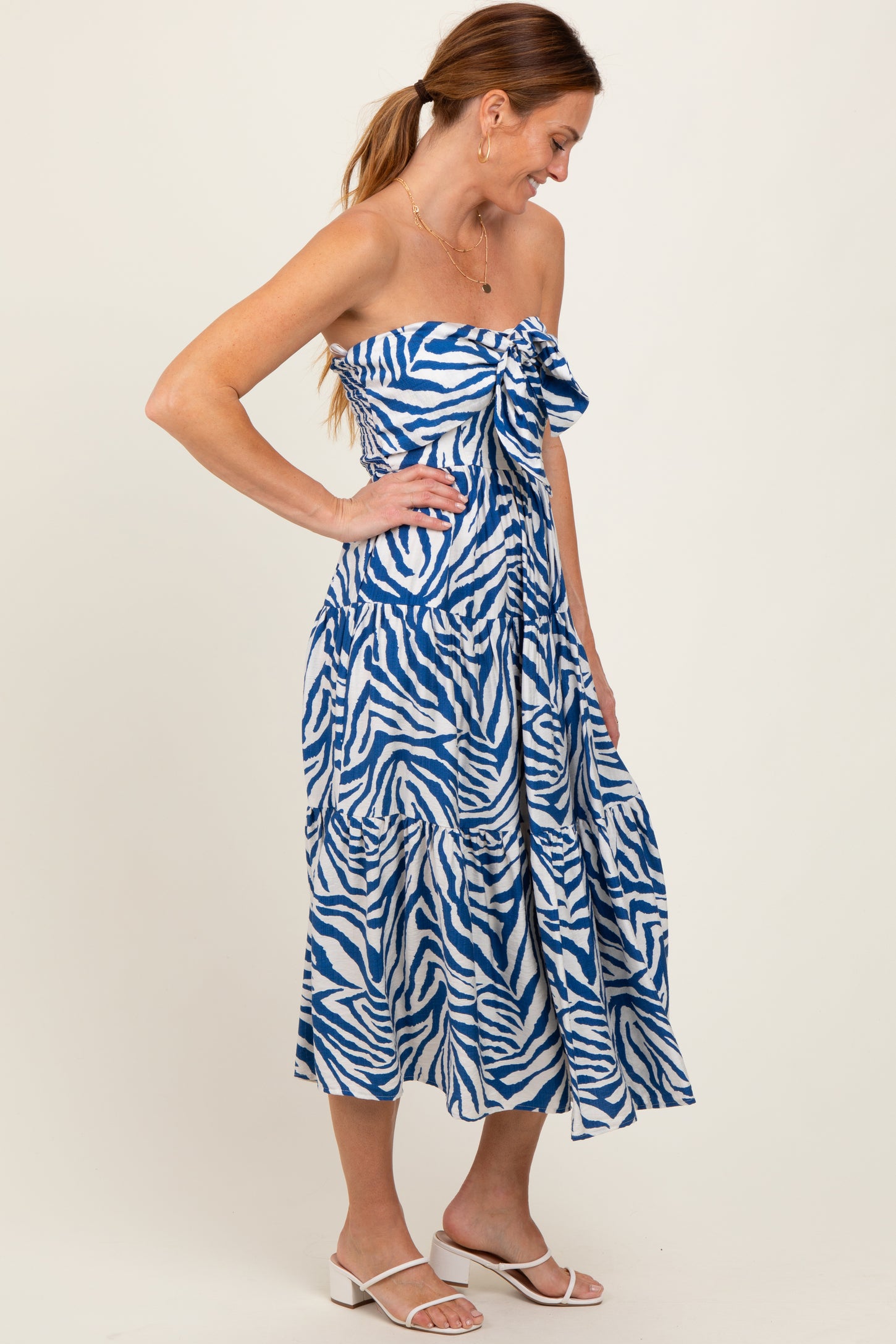 woman wearing a strapless blue and white zebra print maxi dress, standing with one hand on her hip