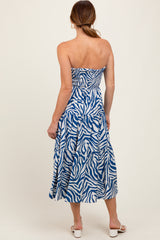 woman wearing a strapless blue and white zebra print midi dress, showing the back view and flowing skirt