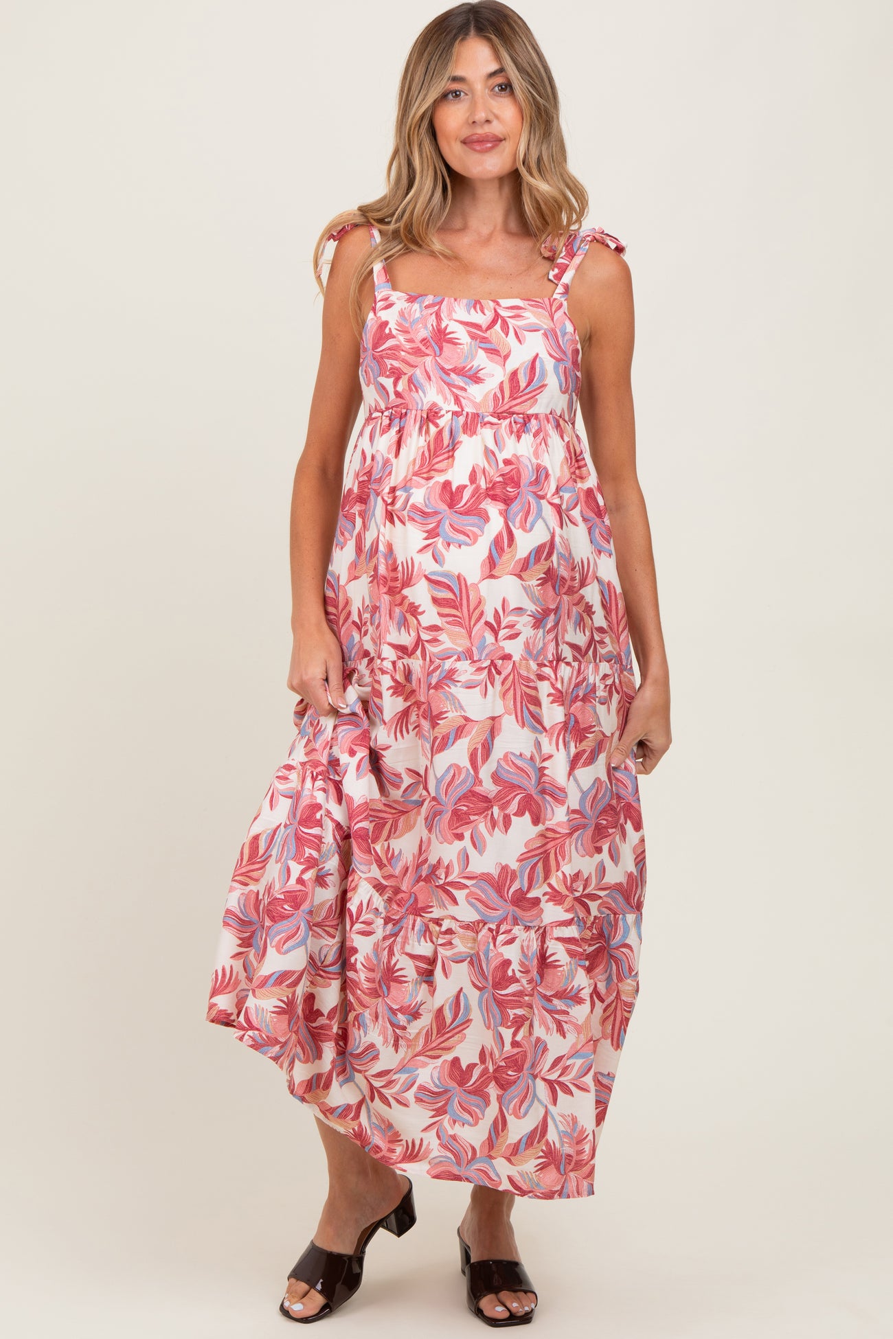 woman wearing a floral patterned maternity maxi dress with adjustable straps and a flowy skirt, showcasing her baby bump