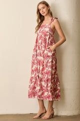 woman wearing a pink floral maxi dress with tie straps and pockets