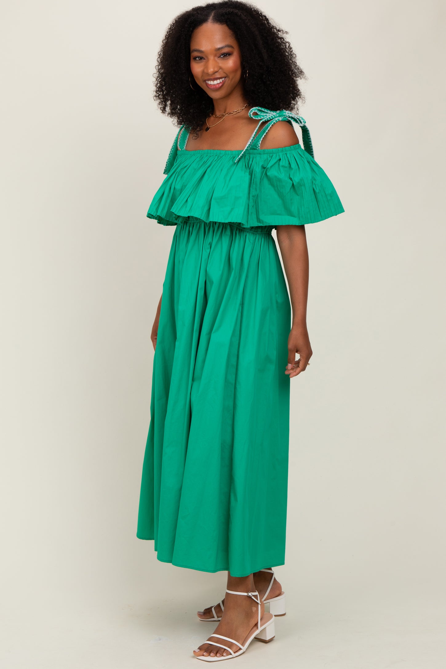woman wearing a green off-the-shoulder maxi dress with ruffled tiers and matching tie straps