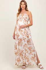 woman wearing a floral print maternity maxi dress with a halter neckline, gently holding her baby bump