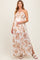 woman wearing a floral print maternity maxi dress with a halter neckline, gently holding her baby bump