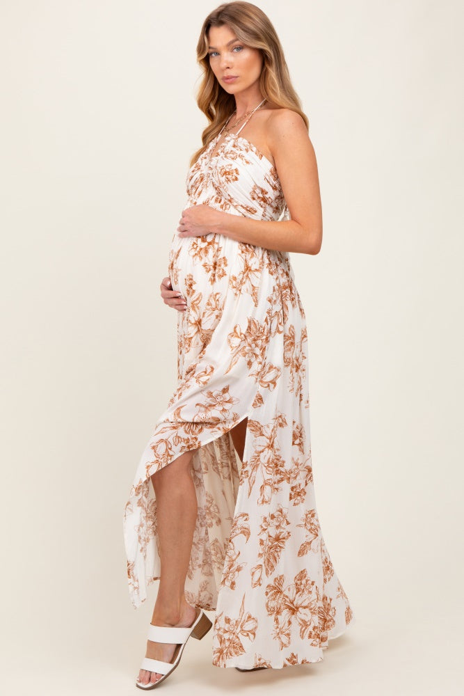 woman wearing a white floral strapless maternity maxi dress, showing her baby bump while posing elegantly