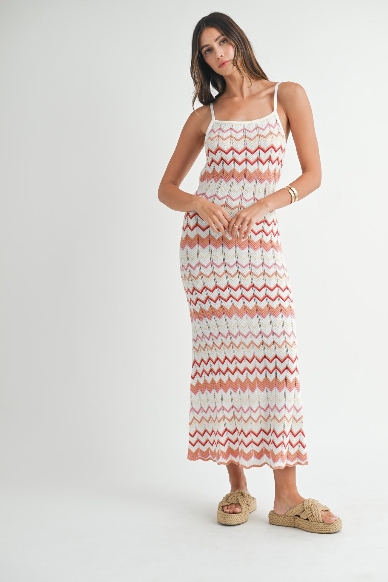 woman wearing a white and coral zigzag patterned maxi dress with spaghetti straps and tan slide sandals