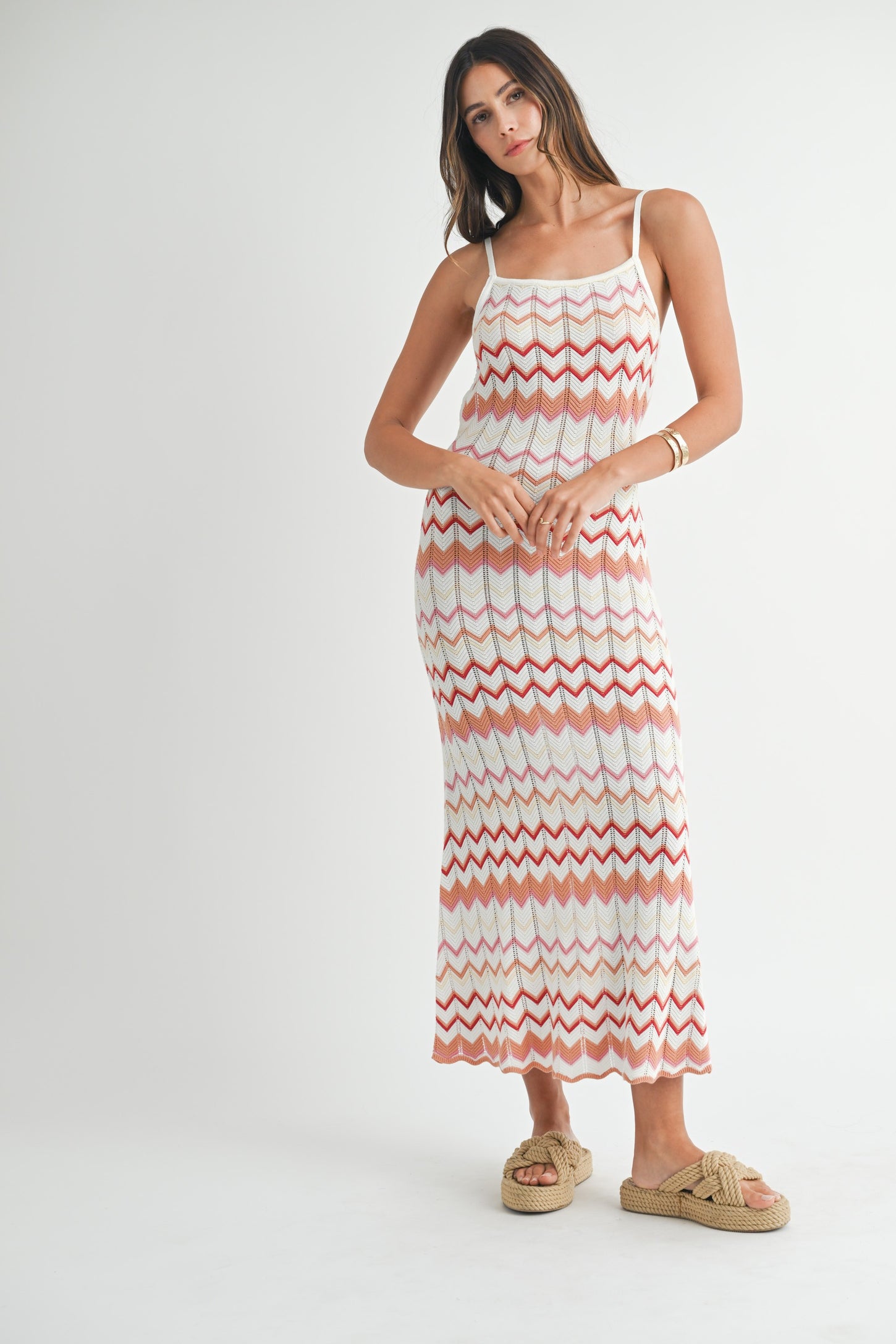 woman wearing a white and coral zigzag patterned maxi dress with spaghetti straps and tan slide sandals