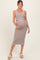 woman wearing a multi-colored striped maternity dress with cutouts and holding her baby bump