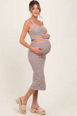 woman wearing a multicolored striped maternity dress and holding her baby bump