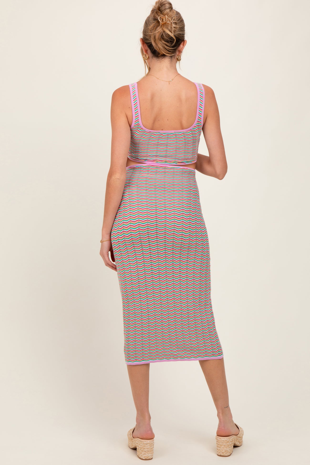 woman wearing a striped maternity midi dress with a fitted silhouette and spaghetti straps, showing a baby bump from the back
