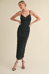 woman wearing a black ruched midi dress with spaghetti straps and a fitted silhouette