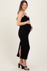 woman wearing a black ruched maternity dress with side slit and showing her baby bump