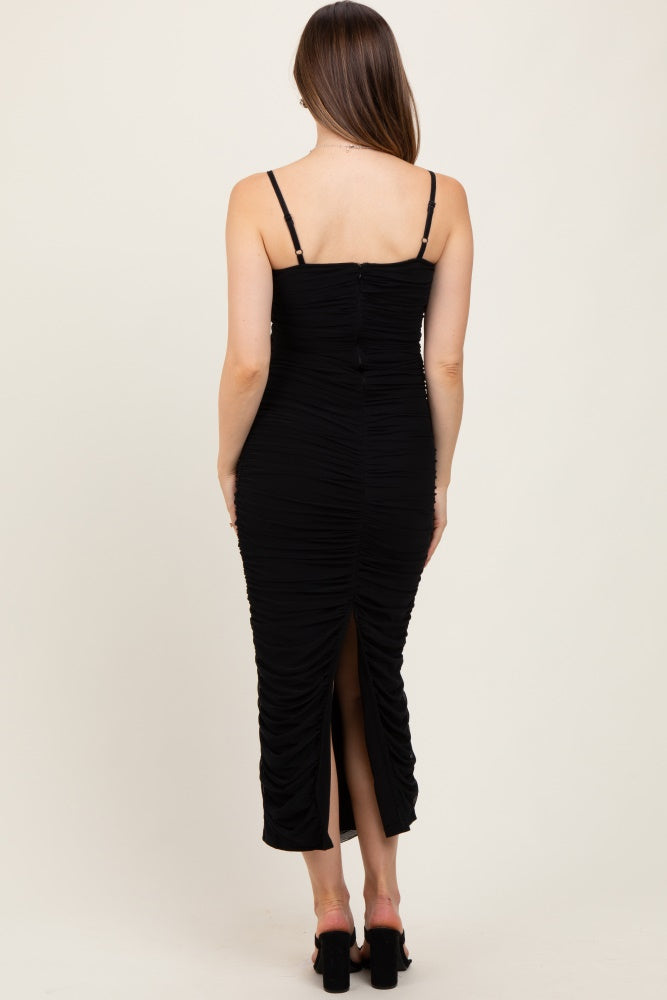 woman wearing a black ruched maternity dress with adjustable straps and a back slit