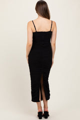 woman wearing a black ruched maternity dress with adjustable straps and a back slit