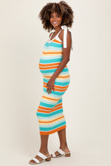 woman wearing a multicolor striped sleeveless maternity dress with tie straps and showing her baby bump